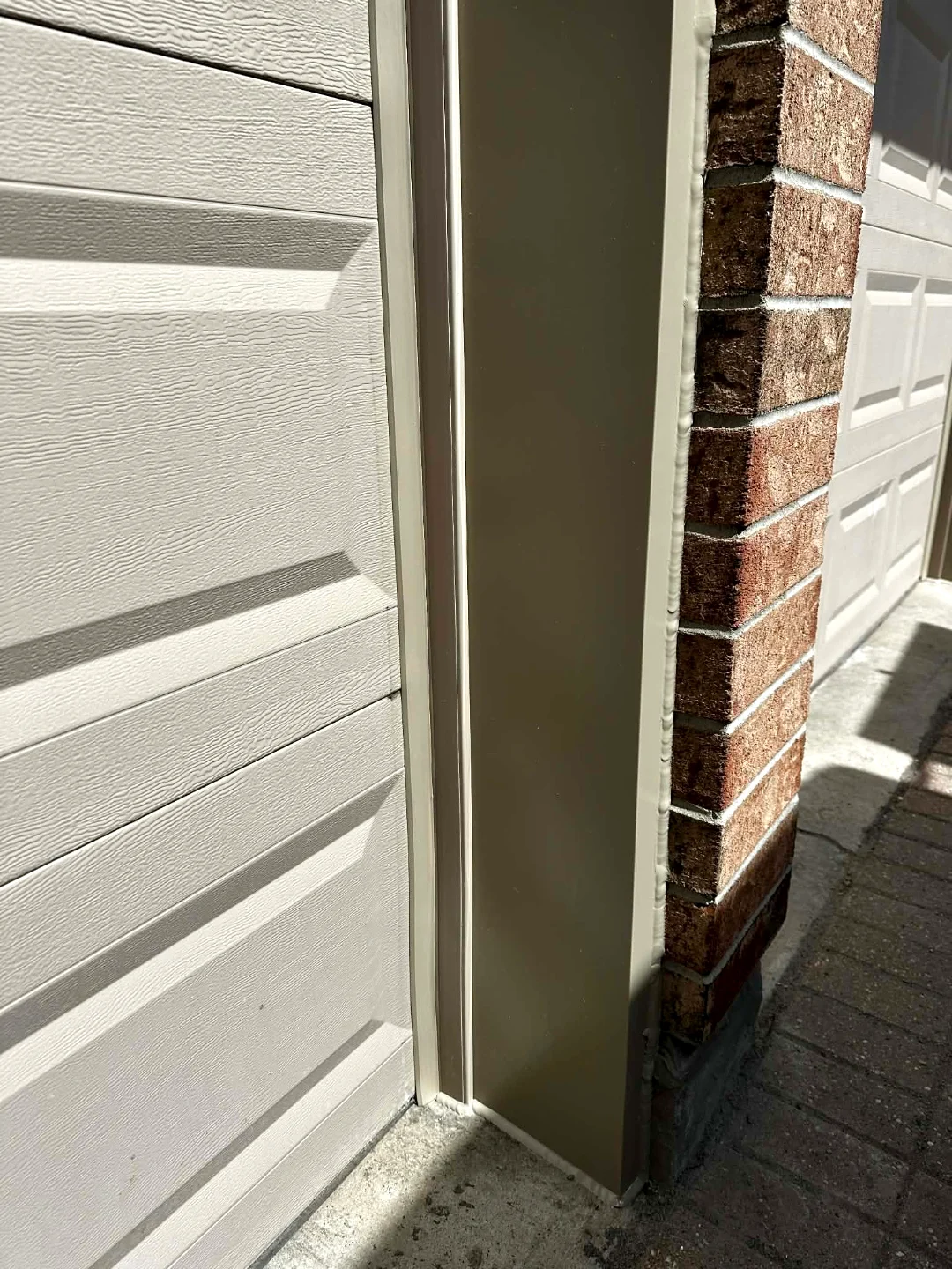 After — Clean almond-colour aluminum capping installed by Liftime around the garage door trim, replacing the rotted wood for good
