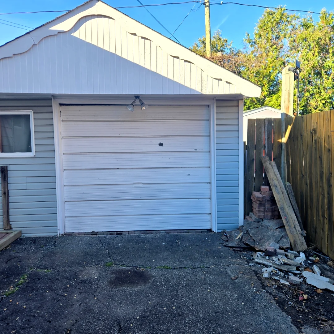Before — Old 1980s-era white horizontal-plank garage door on a back-lane Ottawa garage, paint dulled by decades of weather