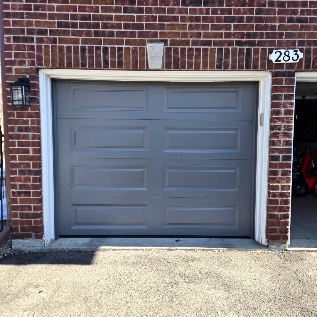 After — Fresh TOHO Heritage 500 long-panel garage door in Charcoal installed by Liftime on the same red brick Ottawa townhome