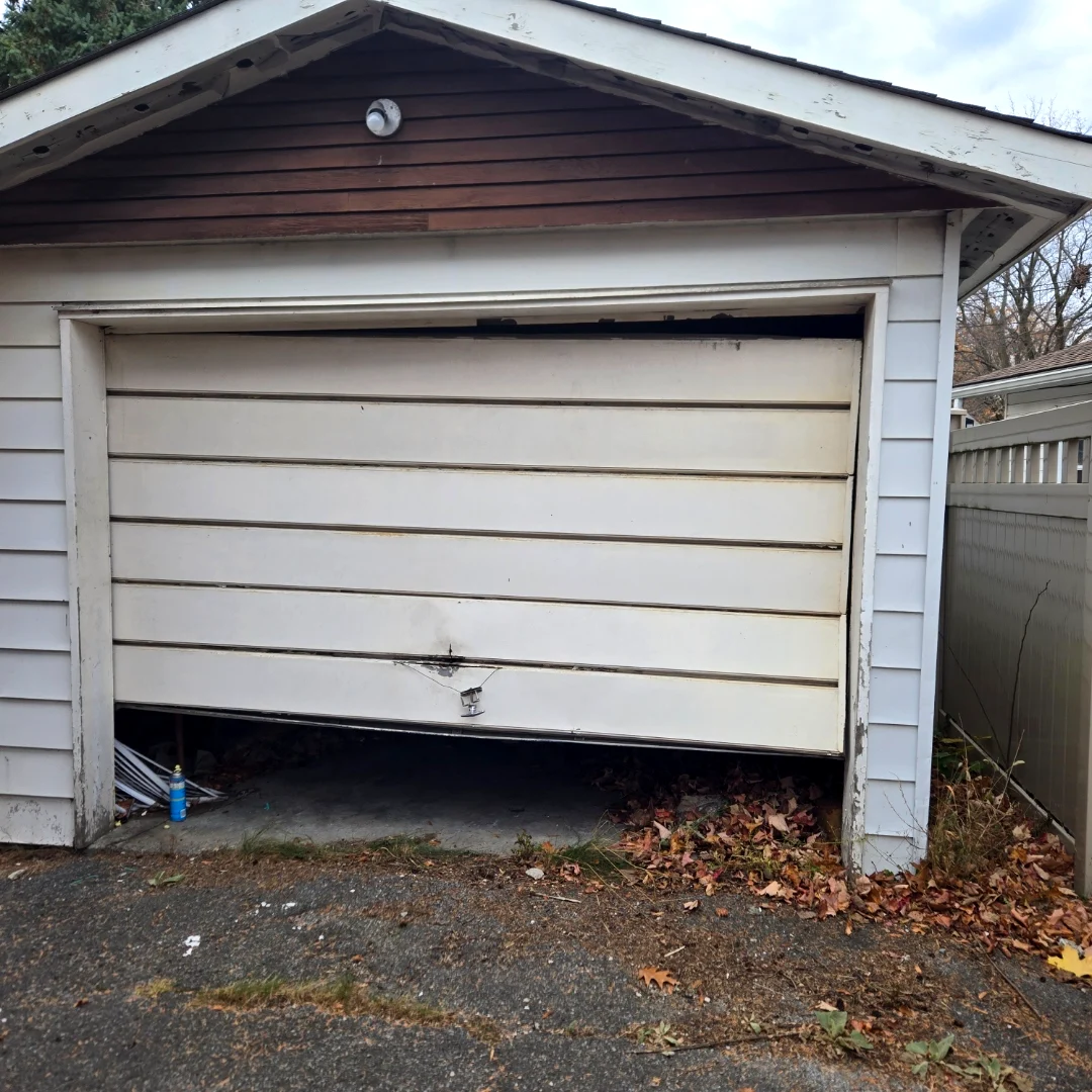 Before — Old non-insulated white horizontal-panel garage door with peeling paint and a visible gap at the top on a detached Ottawa garage