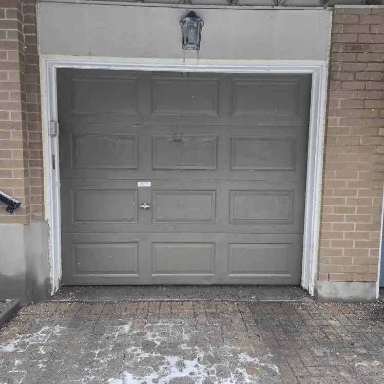 Before — Faded sage green raised-panel single-car garage door on a brick Ottawa home