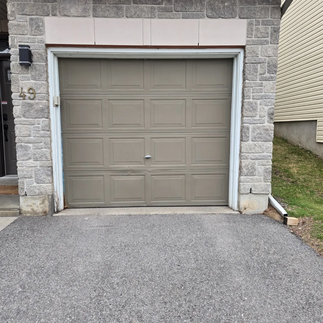 Old beige garage door on an Ottawa stone home before its Liftime replacement