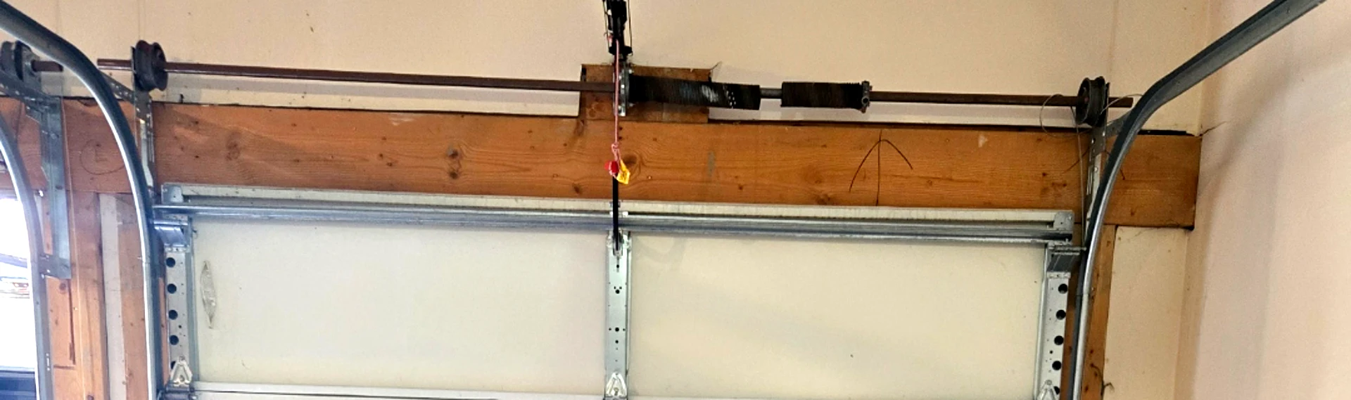 Close-up of a garage door torsion spring with a technician's winding bar