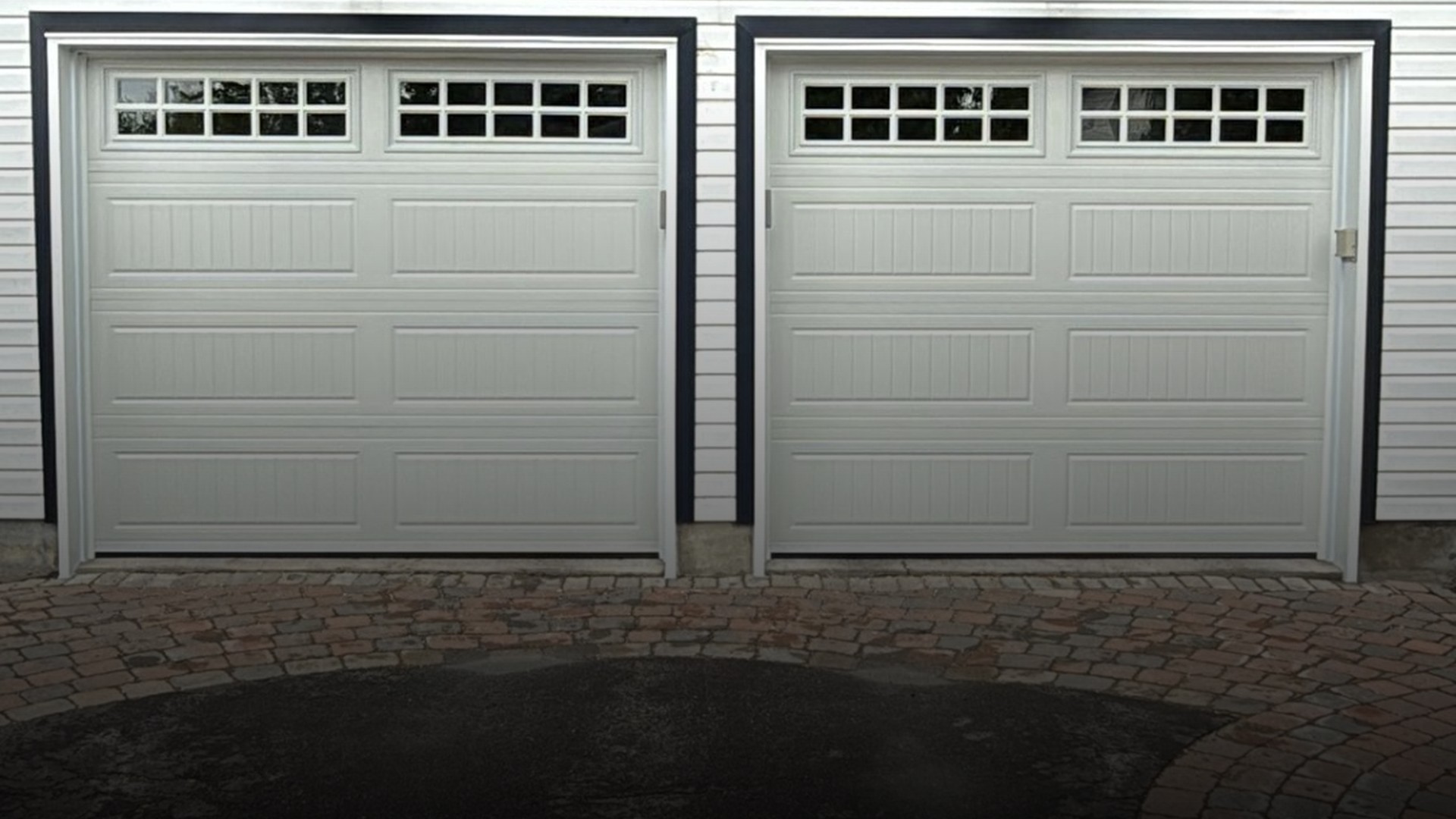 Suburban Ottawa home with double garage doors at dusk — summer evening with dramatic sky and wet driveway