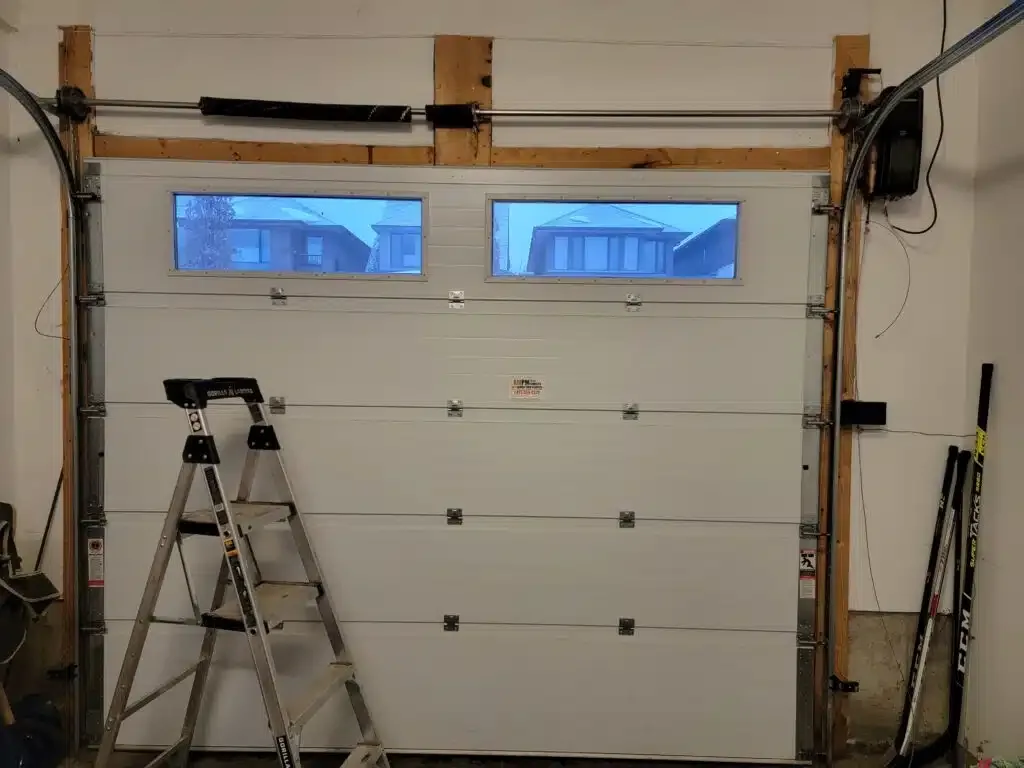 Interior view of a residential garage door with a broken torsion spring and slack cables ready for repair by Liftime in Ottawa
