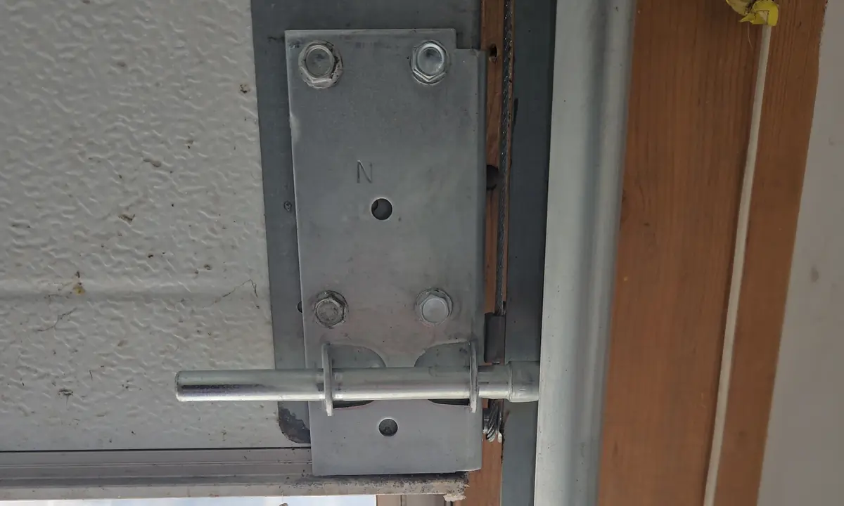 Garage door bottom bracket with the lift cable attached beside the roller and track