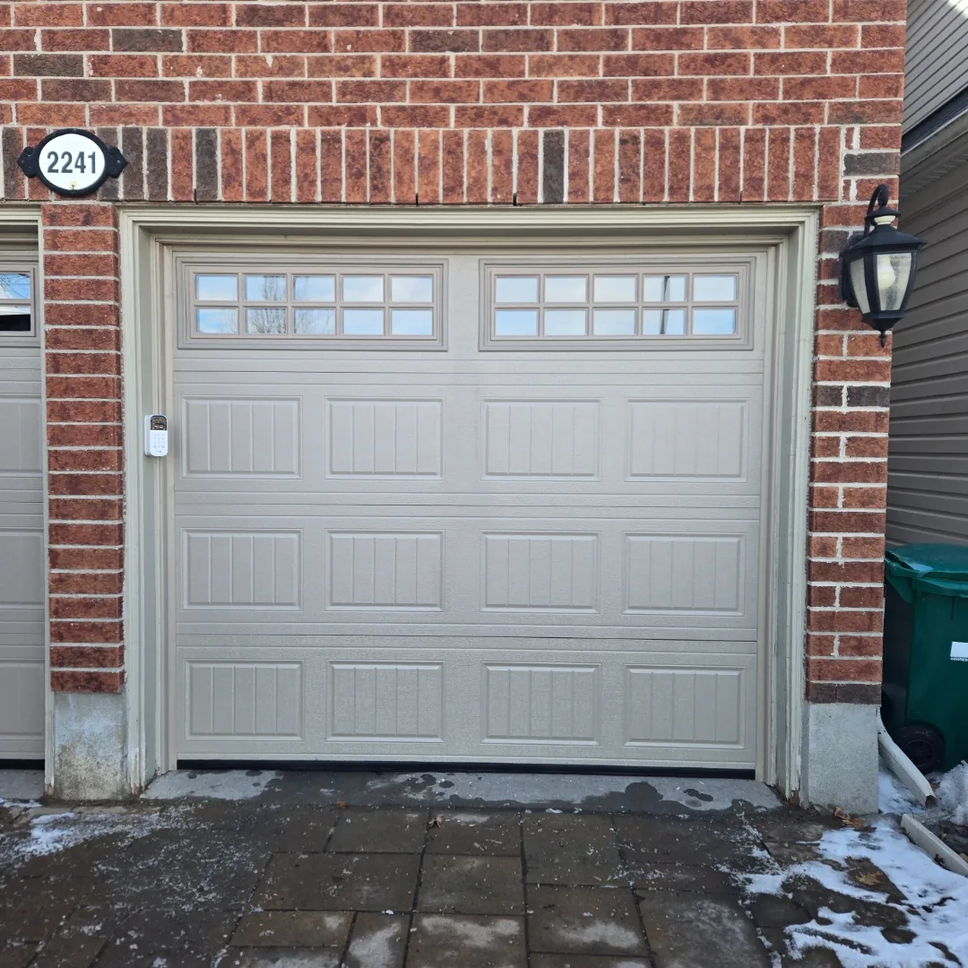 Sandstone raised-panel garage door with windows on an Ottawa brick home — door selection guide