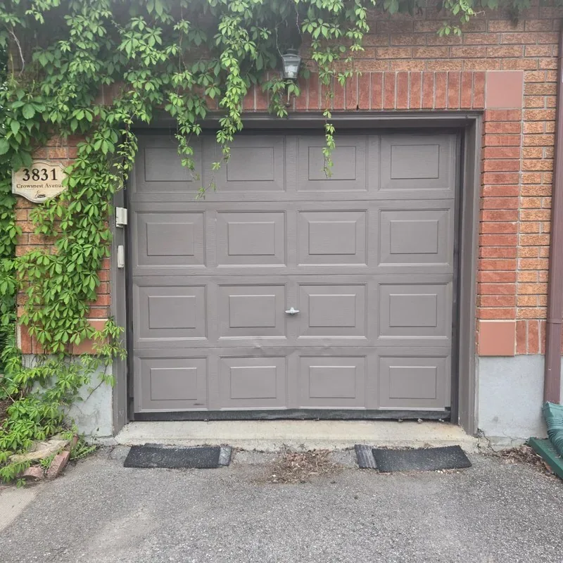 Grey raised-panel garage door on brick Ottawa home with ivy on Crowsnest Avenue — installed by Liftime May 2026