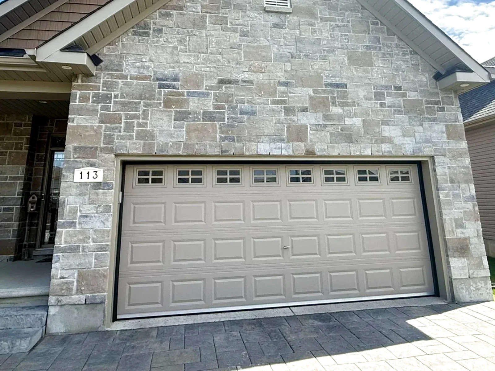TOHO carriage-style garage door in taupe on a stone-front Ottawa home, freshly installed by Liftime