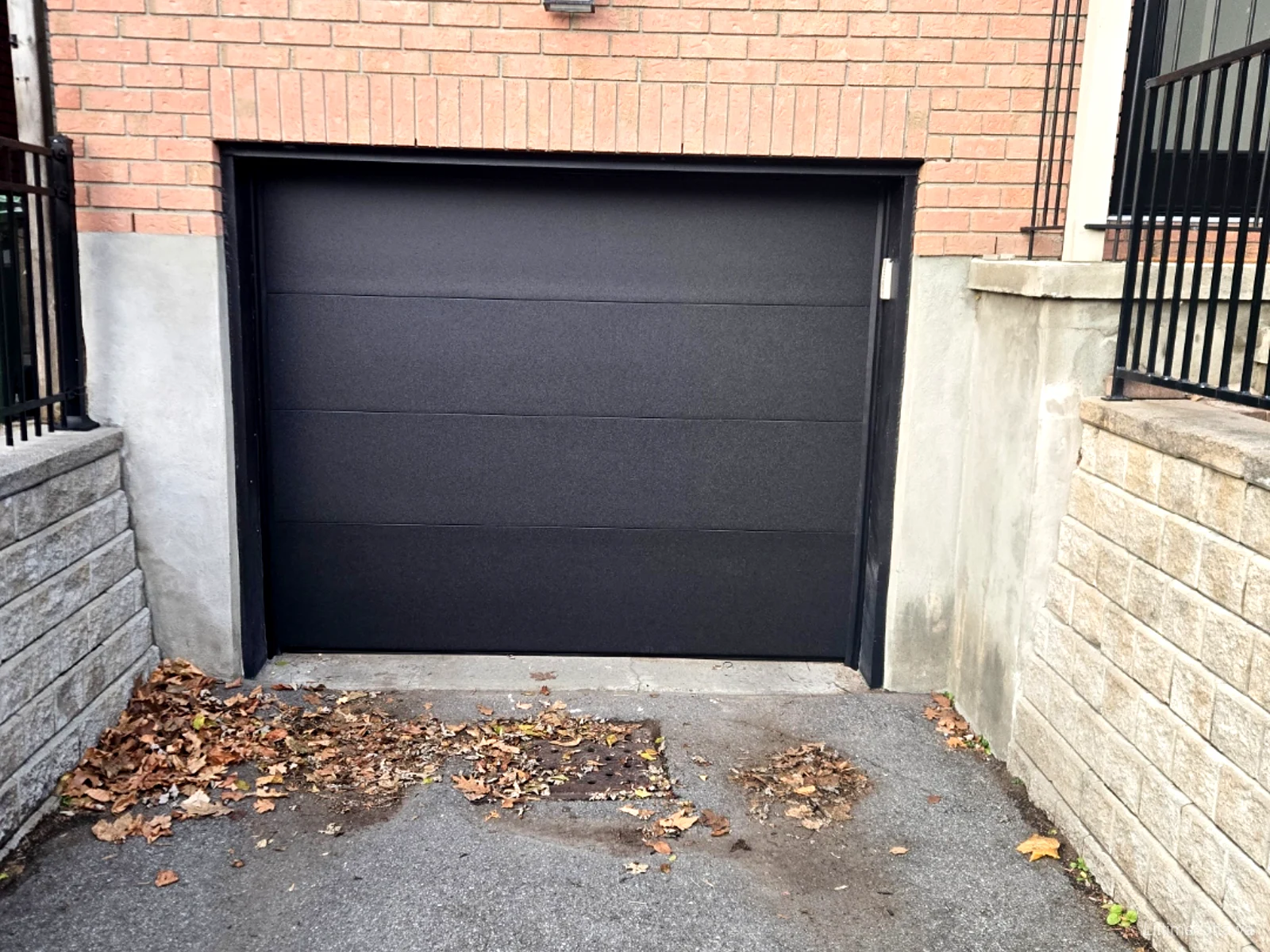 TOHO Flush 800 garage door in black matt finish, installed by Liftime on a red brick Ottawa home