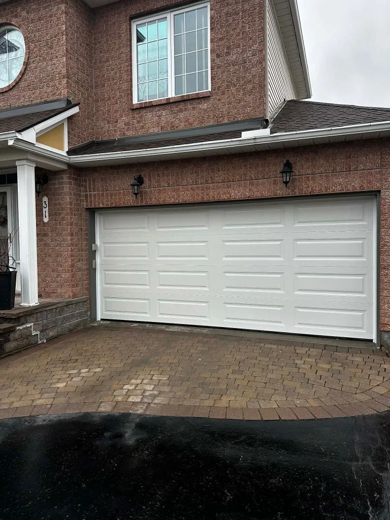Double-car white raised-panel garage door installed by Liftime Ottawa on a red brick home