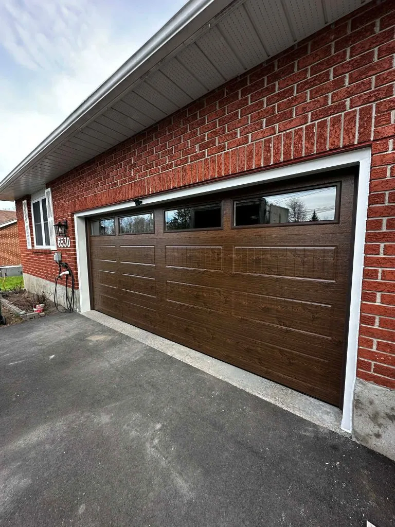 Double-car dark walnut woodgrain garage door with tinted top windows at address 6530 Ottawa