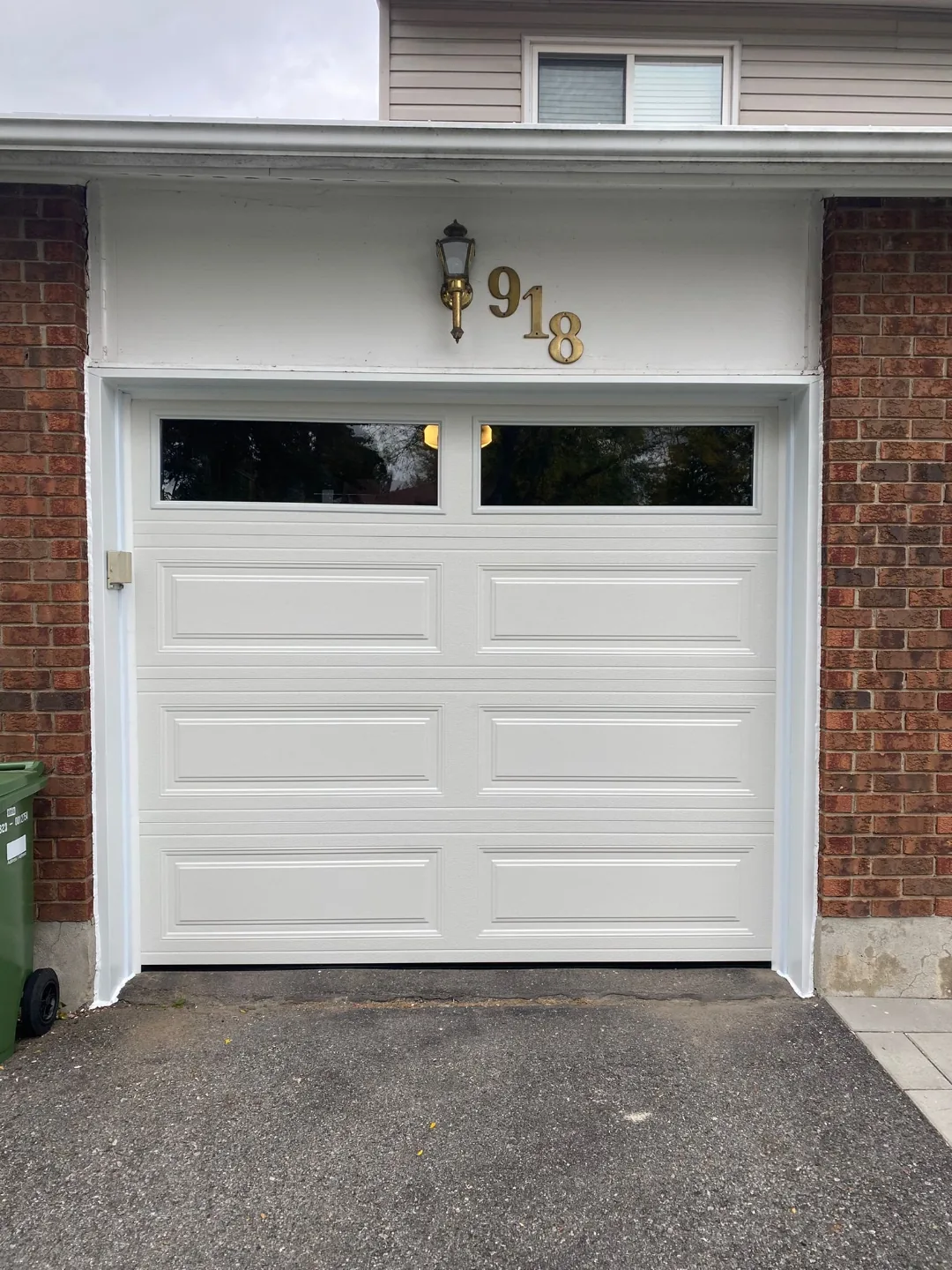 White raised-panel garage door with top windows on brick Ottawa home address 918, installed by Liftime