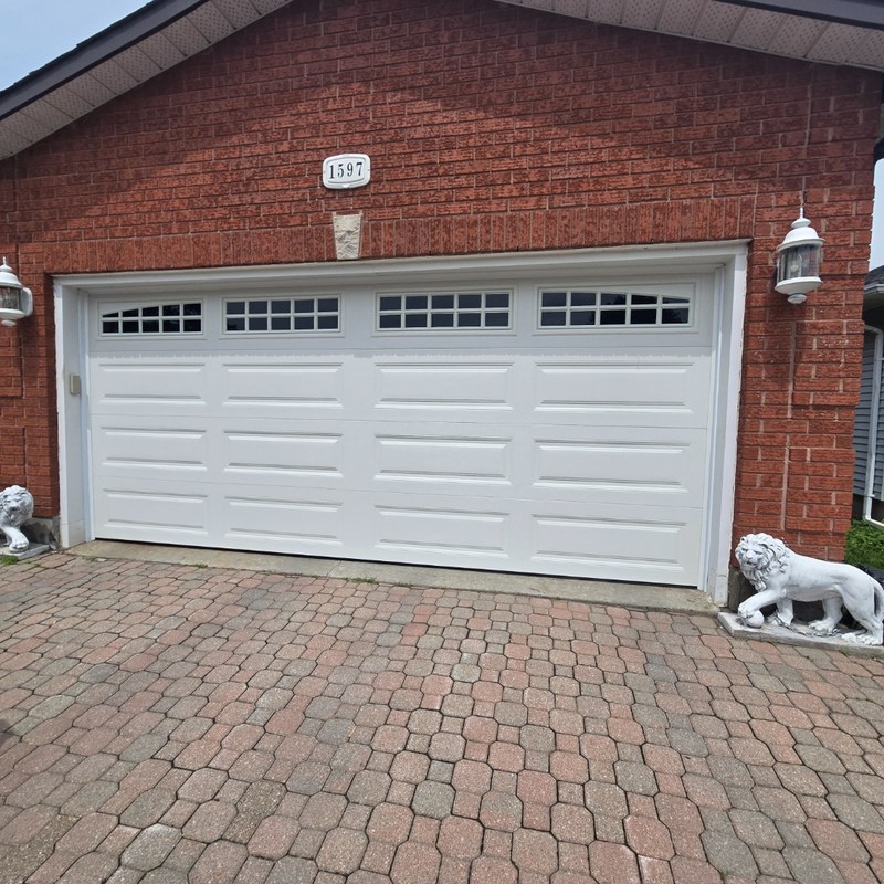 White carriage-style garage door with windows on brick Ottawa home with lion statues — installed by Liftime June 2026