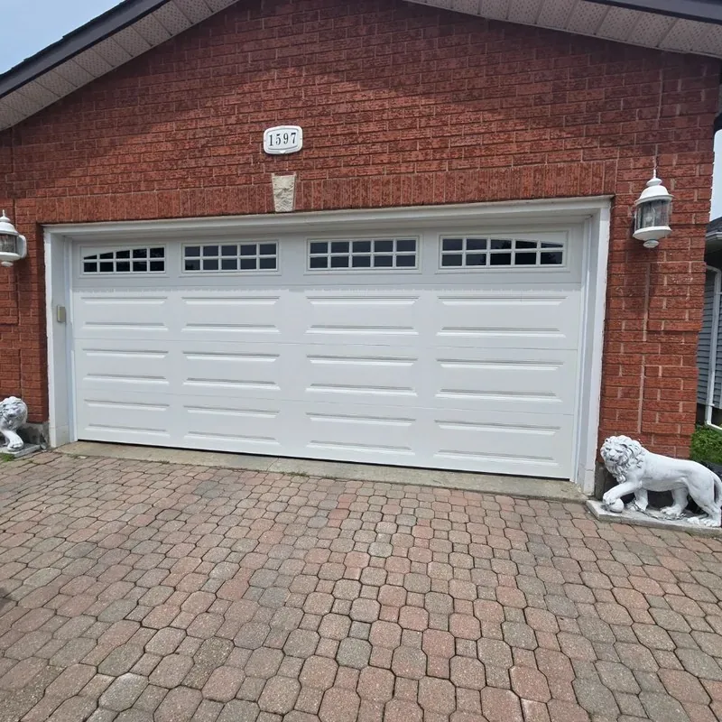 White carriage-style garage door with windows on brick Ottawa home with lion statues — installed by Liftime June 2026