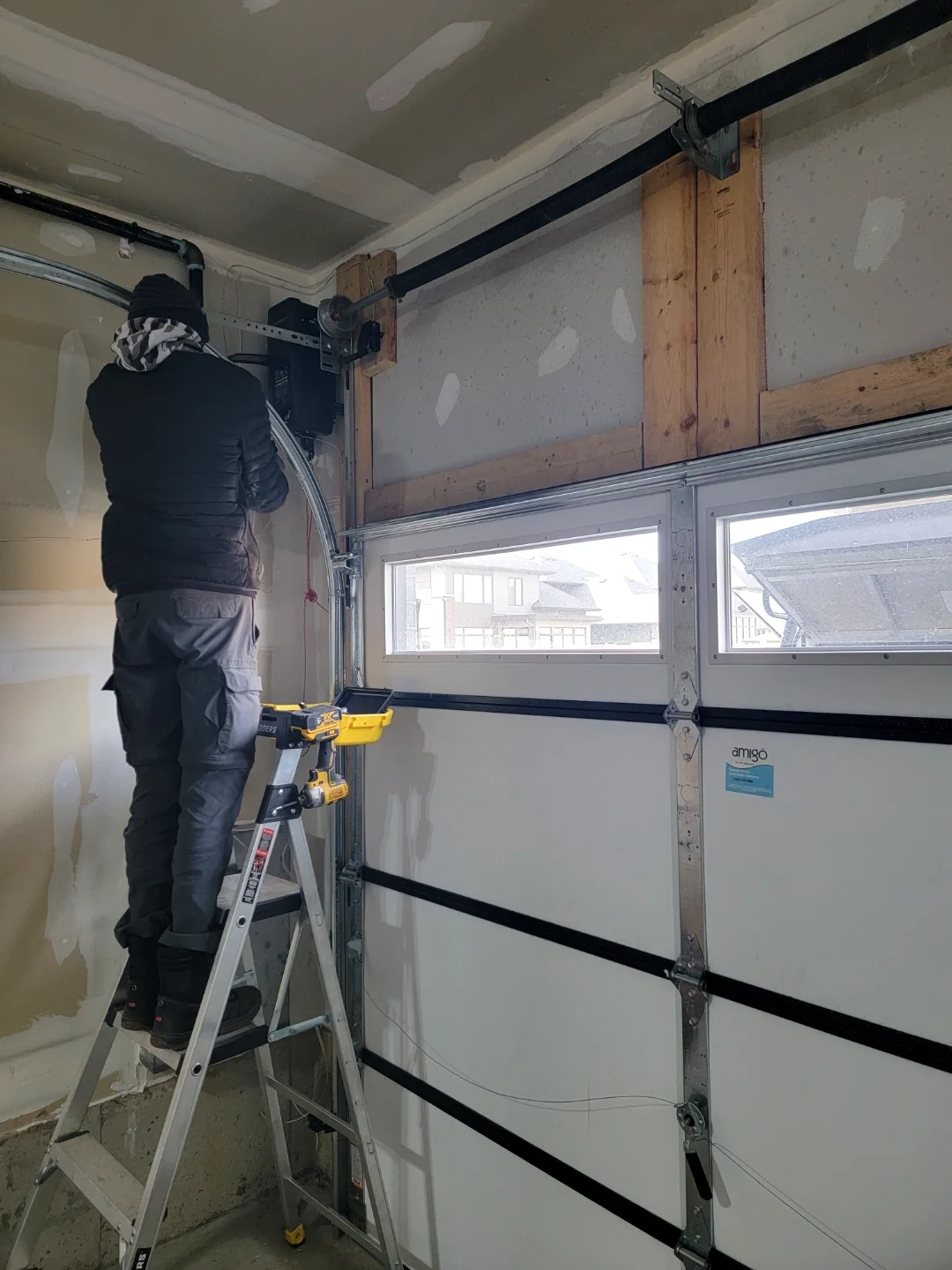 Side-mount jackshaft garage door opener with new cables and torsion drum being installed at the side of the door by Liftime