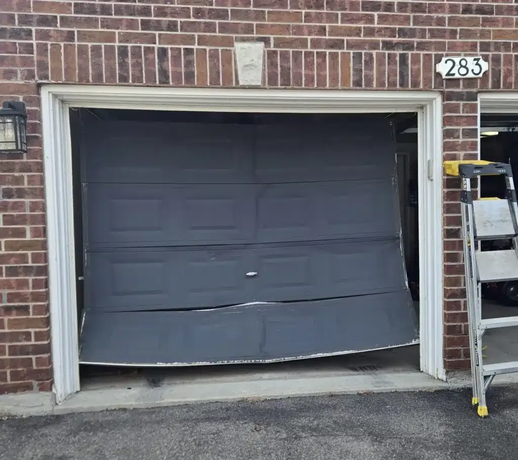 Damaged garage door bent at the bottom from a vehicle impact, awaiting emergency repair in Ottawa