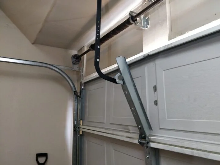 Close-up of a garage door torsion spring bracket and shaft assembly during repair