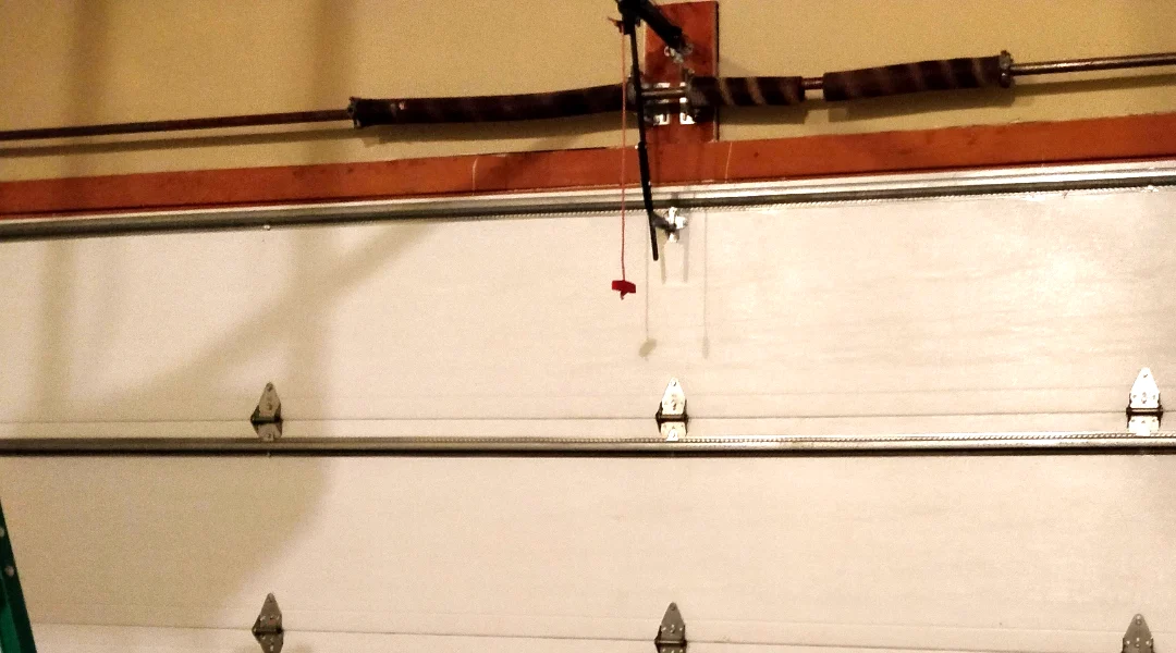 Close-up of a snapped torsion spring on the shaft above a garage door with a clear gap between the broken coils — a typical Ottawa spring failure Liftime repairs